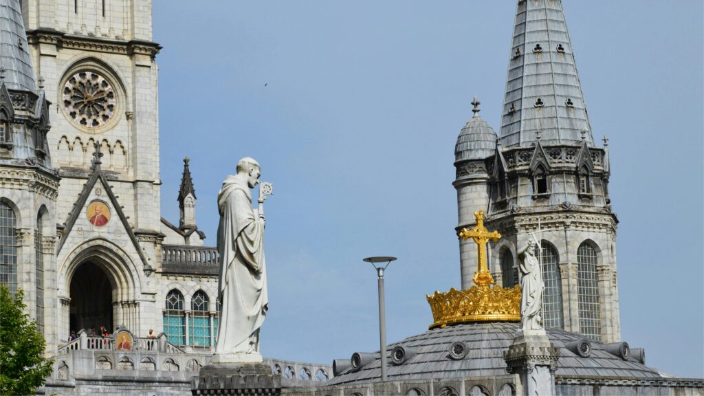 Stunning view of the Basilica of Lourdes with statues and cross under a clear sky.