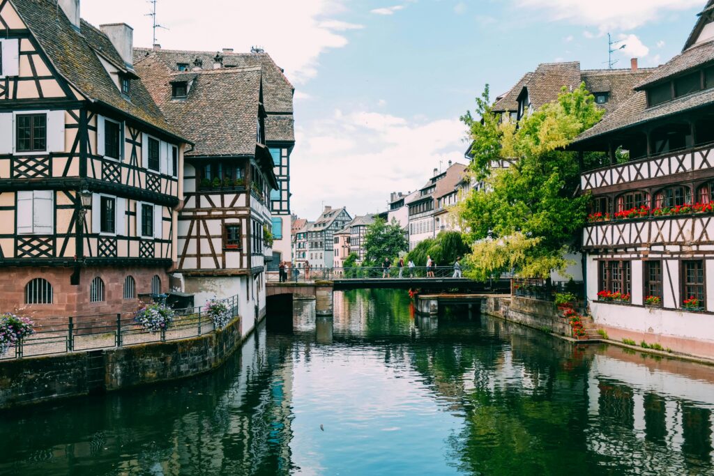 Picturesque scene of half-timbered houses along a tranquil canal in Strasbourg, France.