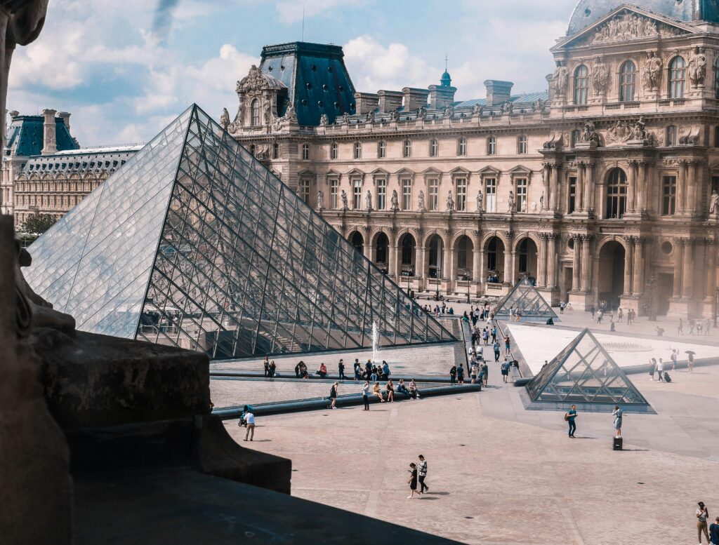 View of the Louvre Museum and iconic glass pyramid in Paris, a top tourist destination.