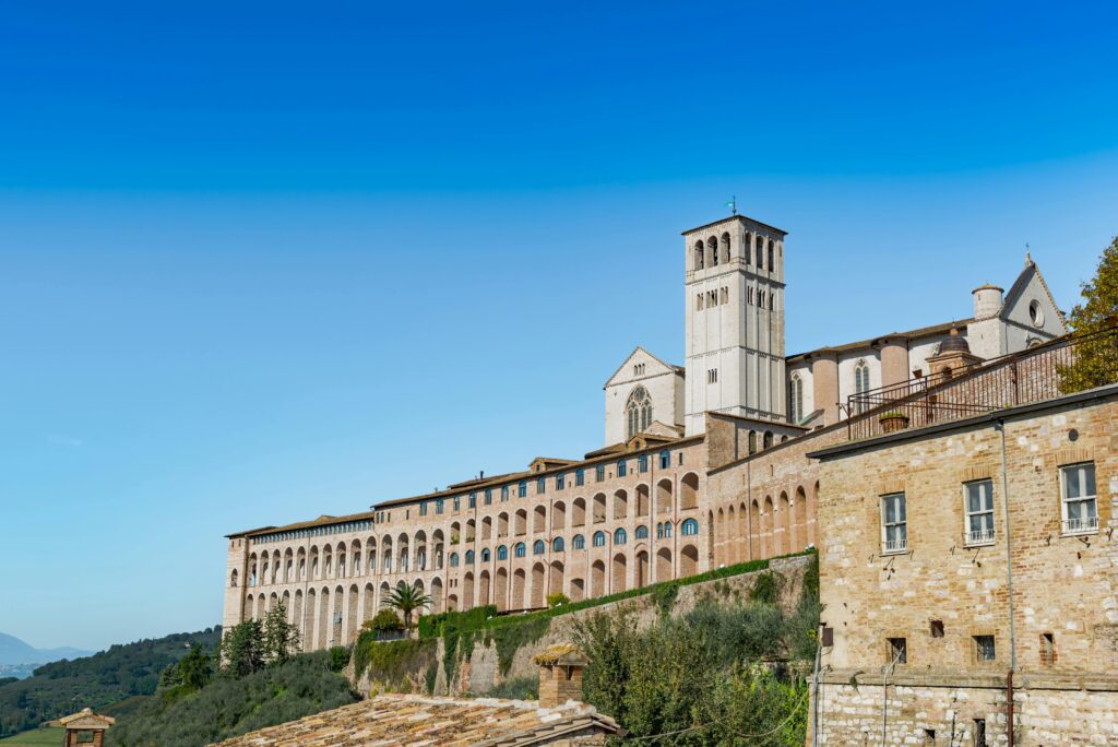 Basilica of Saint Francis in Assisi under clear blue skies, showcasing historic architecture.