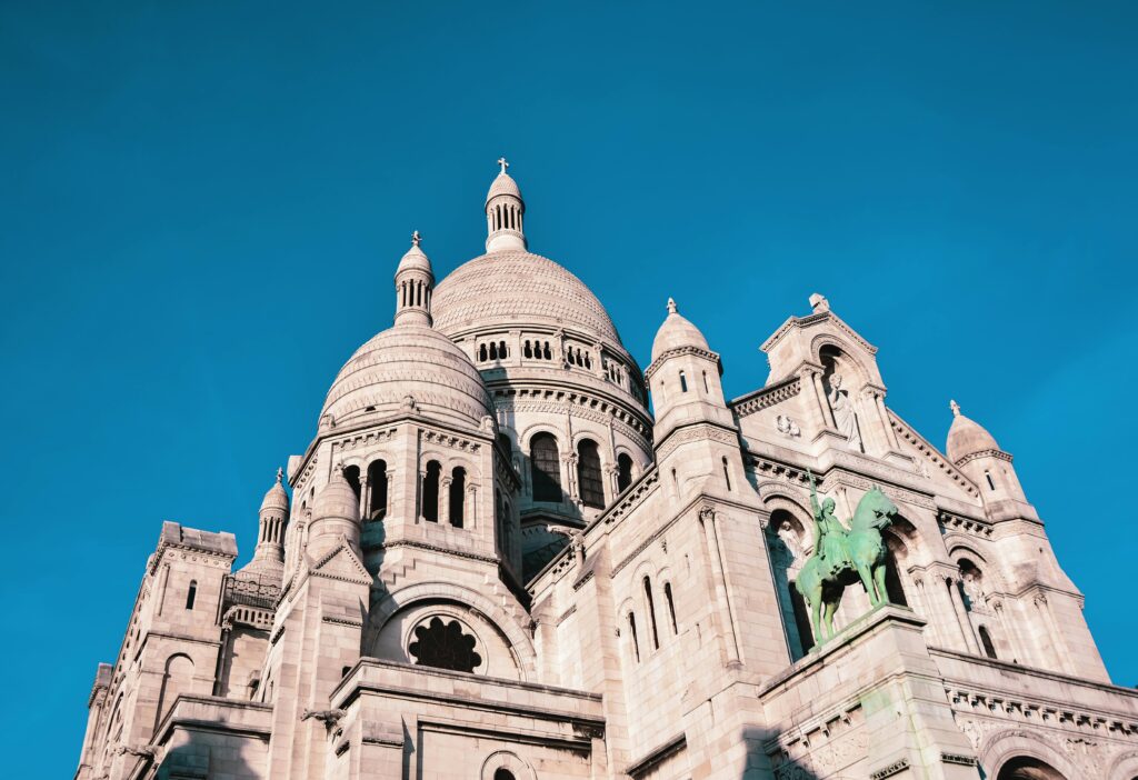 View of the Sacré-Cœur Basilica's architectural grandeur in Paris with a vibrant blue sky.