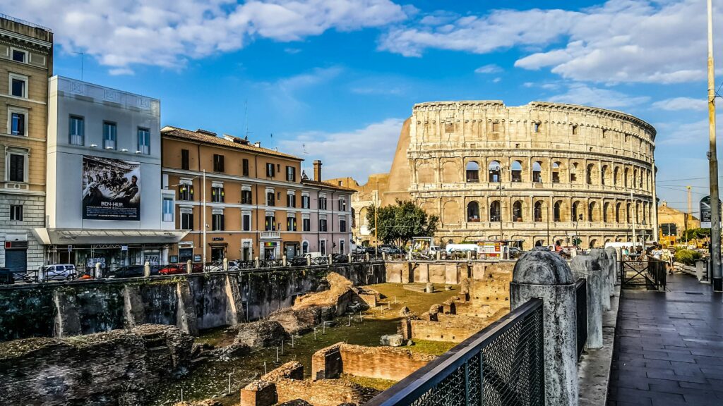 Daylight view of the historic Colosseum in Rome with vibrant city buildings.